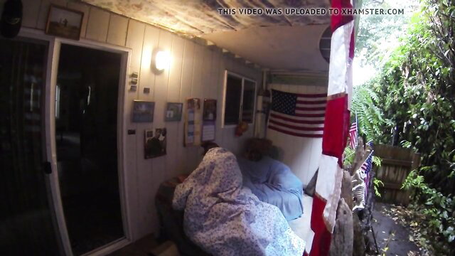 Mature couple cuddling under blanket on rainy patio