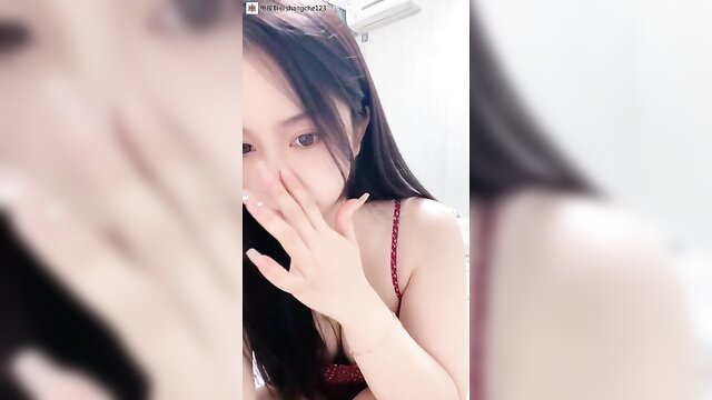 Young Chinese girl in red lingerie covers mouth shyly, closeup tease