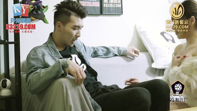 Busty Asian milf topless with huge tits chats intimately with man on couch