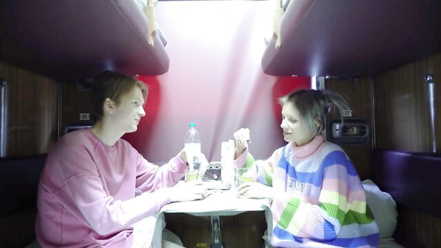 Cute Euro couple in cozy train compartment sipping drinks intimately