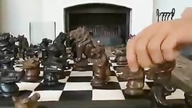 Two friends playing chess with a hand moving a piece